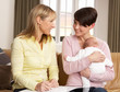 Mother With Newborn Baby Talking With Health Visitor At Home