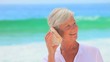 Elderly white-haired woman listening to a shell