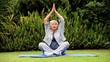 Grey-haired woman practising oriental exercises in garden 