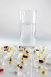 verschiedene Tabletten und Medikamente vor Wasserglas