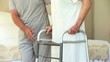 Male nurse helping woman to walk with a zimmer frame