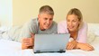 Couple lying down looking at a laptop 