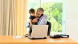 Businessman holding toddler and working