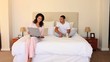 Young couple sitting on their bed sharing a laugh 