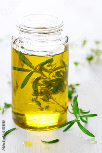 Photo: Scented oil with rosemary and fresh herbs on white wooden backgr Scented oil with rosemary and fresh herbs on white wooden backgr