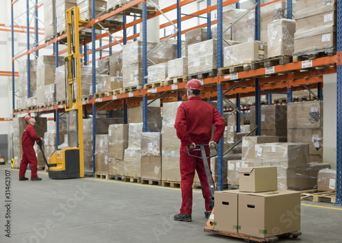 Photo: workers in uniforms and safety helmets working in storehouse workers in uniforms and safety helmets working in storehouse