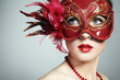 The beautiful young woman in a red mysterious venetian mask