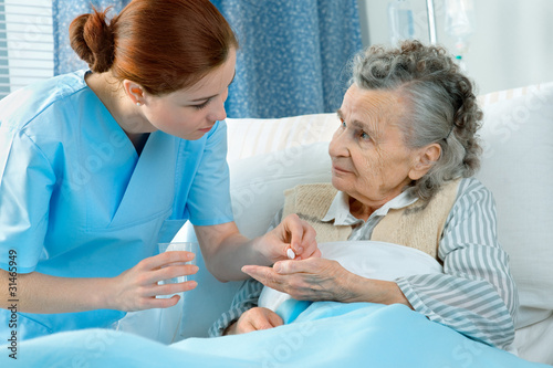 Photo: Nurse cares for a elderly woman lying in bed Nurse cares for a elderly woman lying in bed