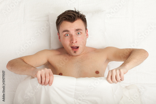 Photo: surprised young handsome man in white bedding, series surprised young handsome man in white bedding, series