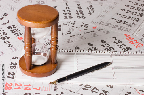 Photo: hourglass on calendar sheets hourglass on calendar sheets