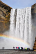Skogafoss waterfall with rainbow, some tourist, Iceland
