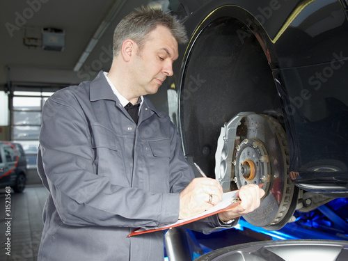 Foto: Master mechanic in a garage is writing an order Master mechanic in a garage is writing an order