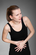 Young woman with stomach issues on grey