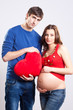 Happy man and pregnant woman with red heart