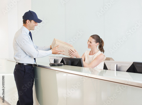 Photo: Delivery man handing box to receptionist Delivery man handing box to receptionist
