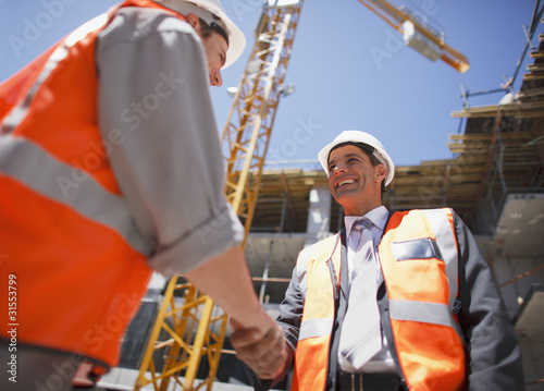 Photo: Construction workers shaking hands on construction site Construction workers shaking hands on construction site