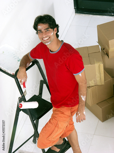 Photo: Joven hombre latino pintando su casa nueva. Joven hombre latino pintando su casa nueva.