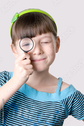 Photo: The girl looks through a magnifier The girl looks through a magnifier