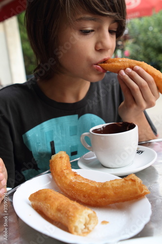 Photo: Junge mit Churros und Schokolade Junge mit Churros und Schokolade