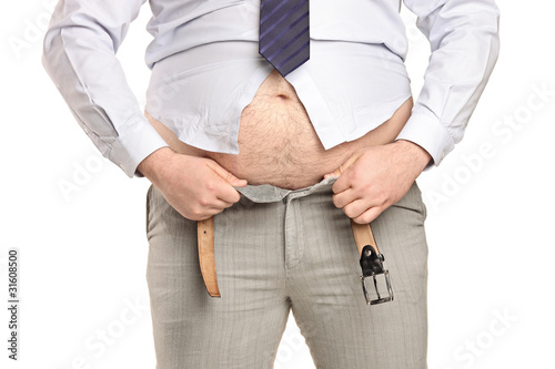 Photo: Overweight man trying to fasten too small clothes Overweight man trying to fasten too small clothes