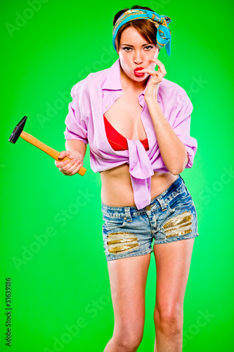 Photo: Woman licking fingers striked by hammer. Pin-up and retro style. Woman licking fingers striked by hammer. Pin-up and retro style.