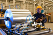 Foto: Factory worker processing roll of steel sheet. Factory worker processing roll of steel sheet.