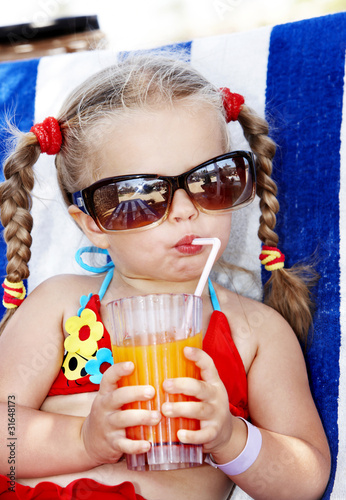 Photo: Child in glasses and red bikini drink juice. Child in glasses and red bikini drink juice.