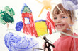 beautiful little girl in red t-shirt paints on glass and smiles
