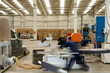 Carpenter cutting wood on electric saw, motion blurred.