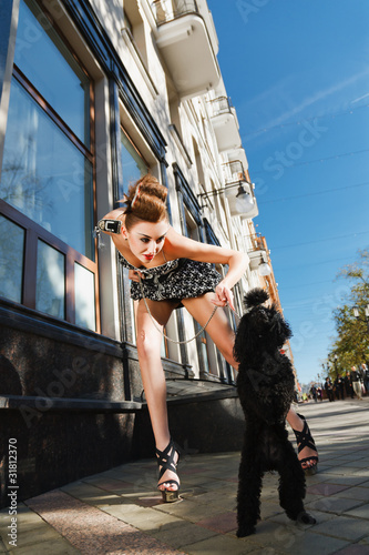 Photo: A girl with a dog standing on the street A girl with a dog standing on the street