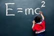 boy drawing E=mc2 on the wall