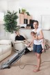 A Mother Trying To Vacuum While The Father Sits Around