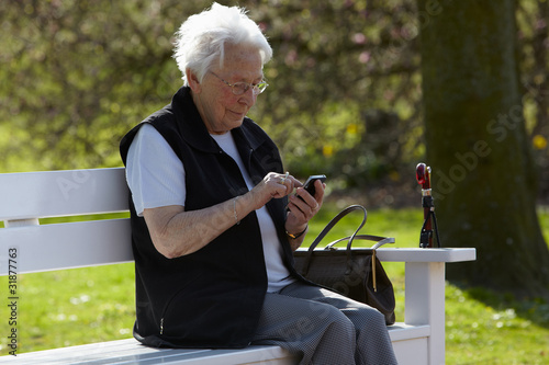 Foto: Nette alte Dame mit Telefon sitzend auf Bank 2 Nette alte Dame mit Telefon sitzend auf Bank 2