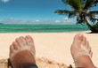 Photo: Relaxing feet on beach. Tropical sea, sky background. Relaxing feet on beach. Tropical sea, sky background.