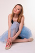 Young woman in dancing suit sits on floor.