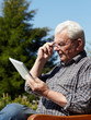 Old handsome man using touchpad e-book reader