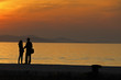 Young couple standing on a jetty at sunset