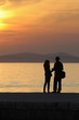 Young couple standing on a jetty at sunset