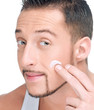Foto: Handsome man applying male creme on face Handsome man applying male creme on face