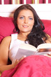 Junge Frau liegt im Bett und liest ein Buch