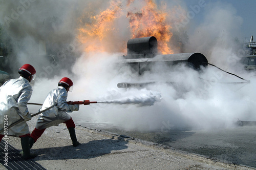 Photo: two Firefighters extinguish a fire with foam two Firefighters extinguish a fire with foam