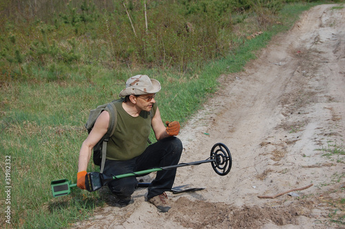Foto: Man with metal detector on the battlefield of WW2 Man with metal detector on the battlefield of WW2