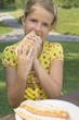 Young Girl Eating A Hot Dog Outdoors