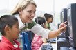 Teacher helping kindergarten children learn how to use computers