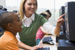 Teacher helping kindergarten children learn how to use computers