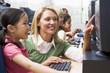 Teacher helping kindergarten children learn how to use computers