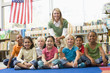 Kindergarten teacher sitting with children in library