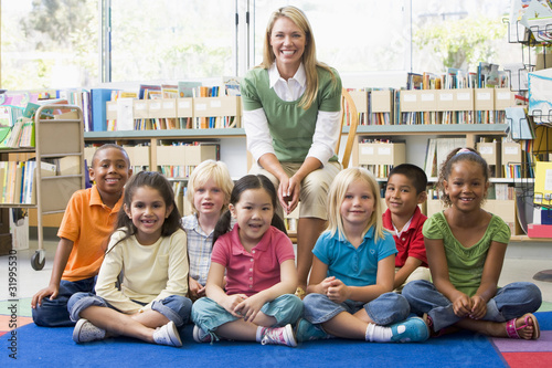 Photo: Kindergarten teacher sitting with children in library Kindergarten teacher sitting with children in library