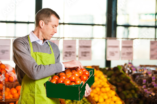 Photo: Market assistant holding box of tomatoes Market assistant holding box of tomatoes