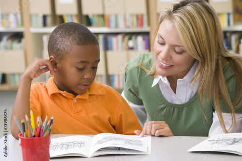 Photo: Kindergarten teacher helping student with reading skills Kindergarten teacher helping student with reading skills